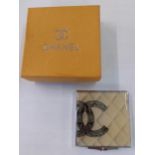 A vintage Chanel double mirror compact with iconic double CC logo on a white tone background, with