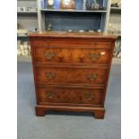 A reproduction burr yew veneered small chest of three long drawers having a brush slide and