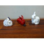Three model rabbits, comprising two Royal Crown Derby paperweights and a Royal Doulton flambe glazed