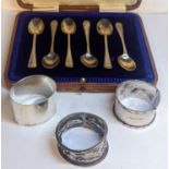 A cased set of six silver spoons together with three mixed napkin rings A/F, total weight 111.6g