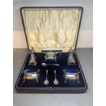 An early 20th century cased set of silver condiments to include salt, pepper, mustard and salts,