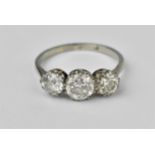 A white metal and three stone diamond ring, with a central brilliant cut stone, roughly 0.84ct,