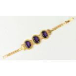 An Egyptian yellow metal and three stone bracelet, possibly synthetic alexandrite, the three oval