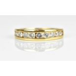 A yellow metal and diamond half eternity ring, with ten channel set diamonds, the shank stamped 14K,