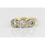 An 18ct yellow and white gold diamond three stone ring, set with three brilliant cut diamonds