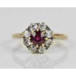 A yellow metal ruby and diamond cluster ring, with a central round cut ruby in an eight claw setting