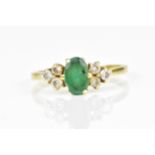 An 18ct yellow gold, emerald and diamond dress ring, with central oval cut emerald flanked by