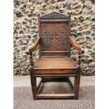 An 18th century carved oak wainscott armchair, the back panel carved with stylised foliage,