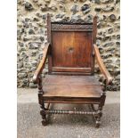 An 18th century carved oak wainscott armchair, the back panel carved with central patera,