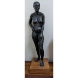 A 20th century black finished wax nude model of a woman on a wooden base, 55cm high