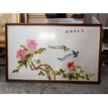 An oriental silk picture of birds flying amongst floral settings