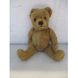 A vintage jointed teddy bear with amber glass eyes, lump to back Location: