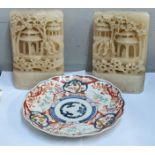 A pair of soapstone carvings and a Japanese Imari plate