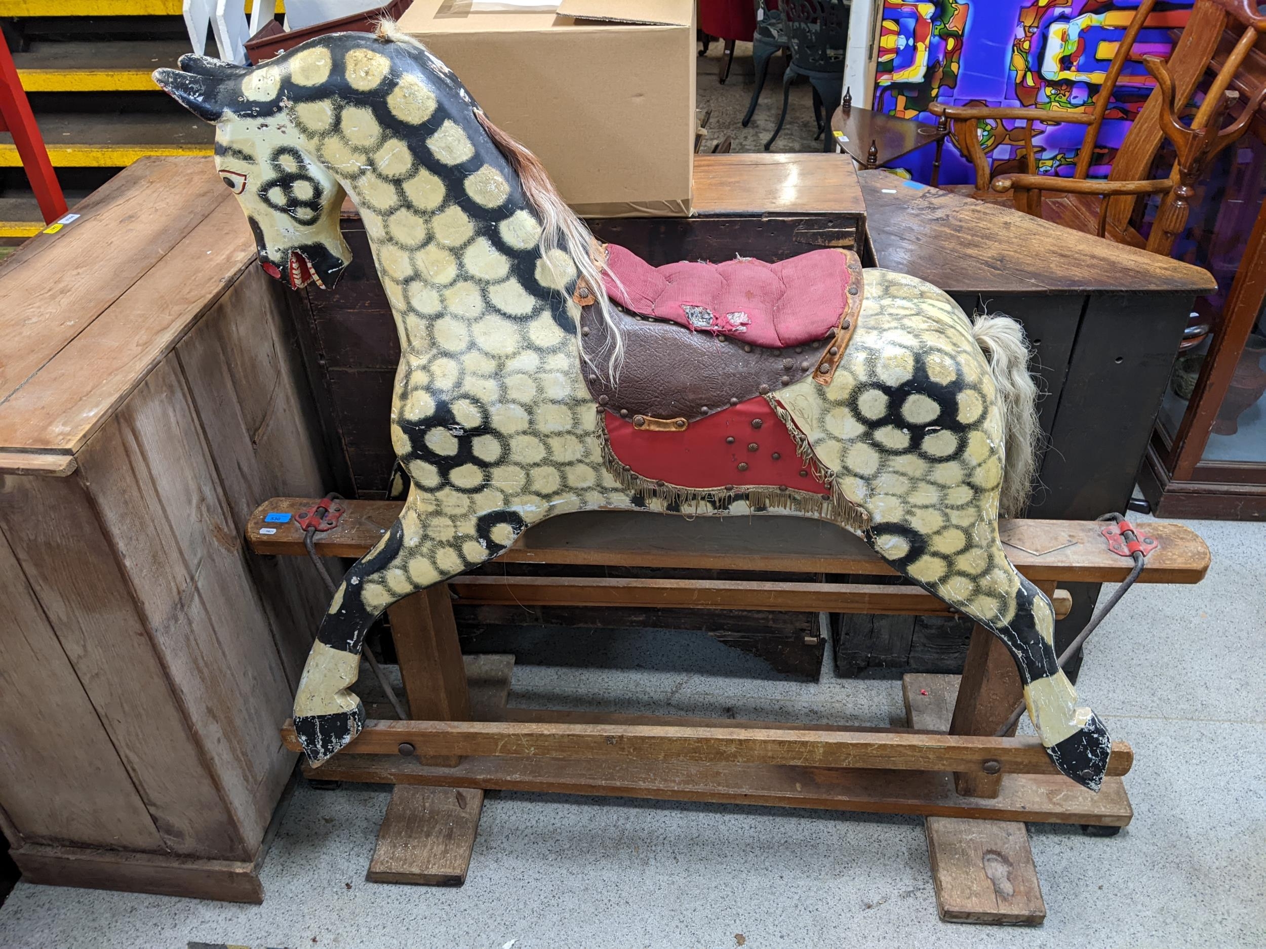 A large early 20th century painted wooden rocking horse with a mane saddle and tail, on a swing base