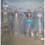 Four decanters to include silver collared examples and a claret jug together with 2 additional