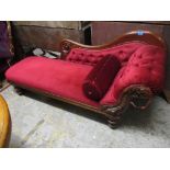 A Victorian mahogany chaise longue with carved decoration, upholstered in a red dralon, on turned