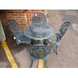 A dark green painted metal garden table and four matching chairs, the circular two tier table with