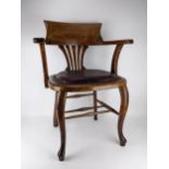 An early 20th century oak framed desk chair with a curved, splat back and brass stud upholstered