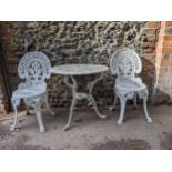 A white painted cast metal garden table and a pair of chairs with pierced scrolled floral ornament