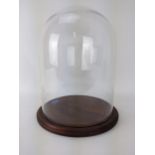 A large glass dome, on a stained turned wooden base, 41cm h, 59.5cm dia Location: