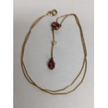 A yellow metal necklace with a drop pendant inset with a seed pearl and pink stones, 2.6g Location: