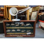 A cased display of Ping golf club heads together with an anglepoise lamp Location: