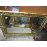 A contemporary gilt framed wall mirror with shell, floral and c-scroll decoration, bevelled glass