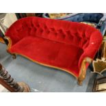 A Victorian button back sofa having a carved walnut serpentine fronted frame with scroll