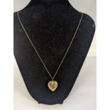 A 9ct gold heart shaped locket, engraved with a bird and flowers on a necklace Location: