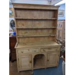 A Victorian pine dresser having a plate rack above two drawers and two panelled doors flanking a '