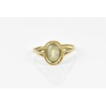 A 9ct yellow gold and clear stone dress ring, with central rub over set oval cut stone, possibly