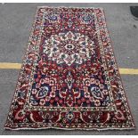 A Persian Bakhtiar hand woven rug having a red ground with a central motif and multiguard borders,
