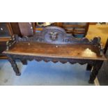 A Victorian oak carved window seat having a raised back with mask motif, 69h x 122w