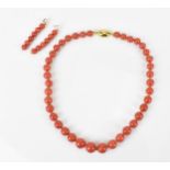 An 18ct yellow gold and red coral single strand bead necklace and pair of matching earrings, the