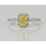 A fancy intense yellow diamond and diamond cluster ring, the cut corner rectangular modern brilliant