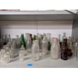 A collection of clear and coloured glass bottles to include J & J Phillips Ltd, Whitmore & Co, and