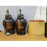 A pair of porcelain chinoiserie style lamps with gilt on a black ground with mustard coloured shades