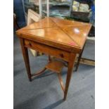 An Edwardian mahogany swivel topped envelope card table having boxwood inlaid with tier below