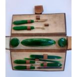 An early 20th Century manicure set with green bakerlite handles housed in a brown leather case.