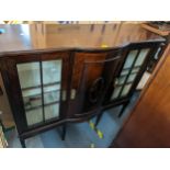 An early 20th century mahogany cabinet having twin glazed doors flanking a bow fronted panelled