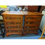 A pair of reproduction yew wood bedside chests of four drawers with brass drop handles and on