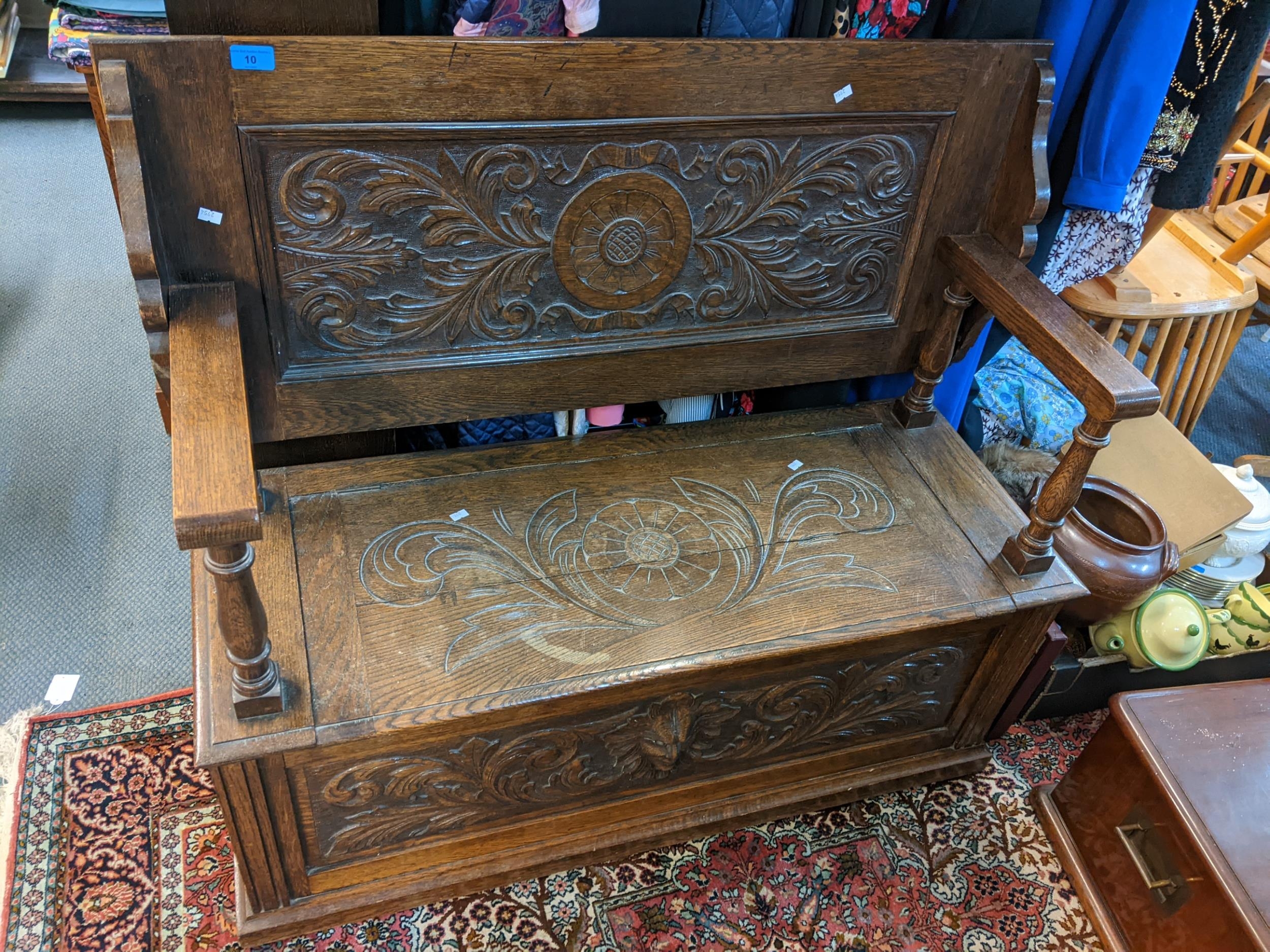 An early 20th century oak carved monk's bench having a hinged seat with storage 96cm h x 106cm w