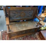 An early 20th century oak carved monk's bench having a hinged seat with storage 96cm h x 106cm w