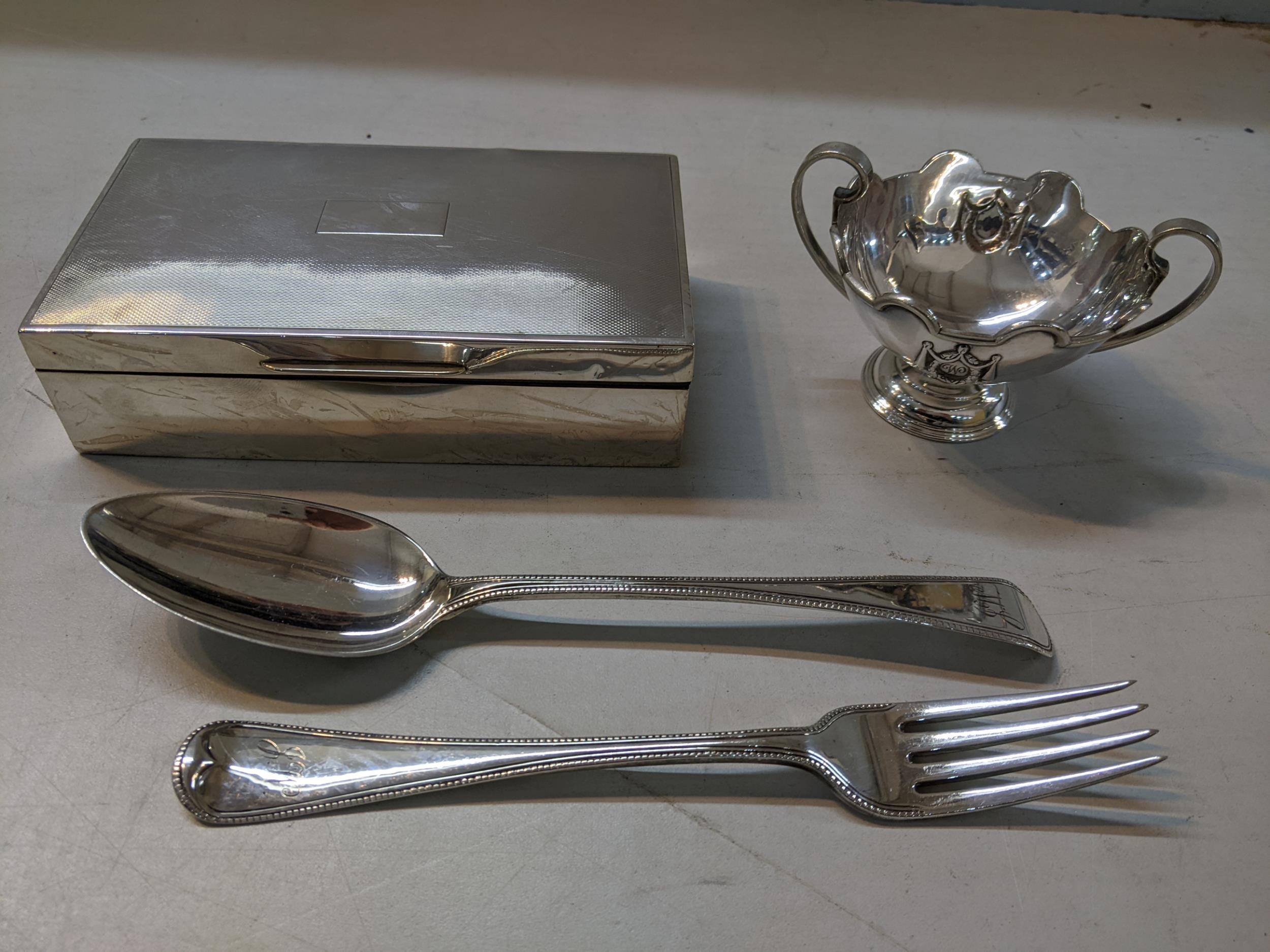 Silver to include a tablespoon and fork, and a sugar bowl 217g, and a cigarette box Location: