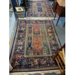 A pair of hand woven Persian blue ground rugs decorated with figures on horseback and tasselled