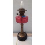 A Victorian oil lamp with cranberry glass reservoir converted to electricity Location: