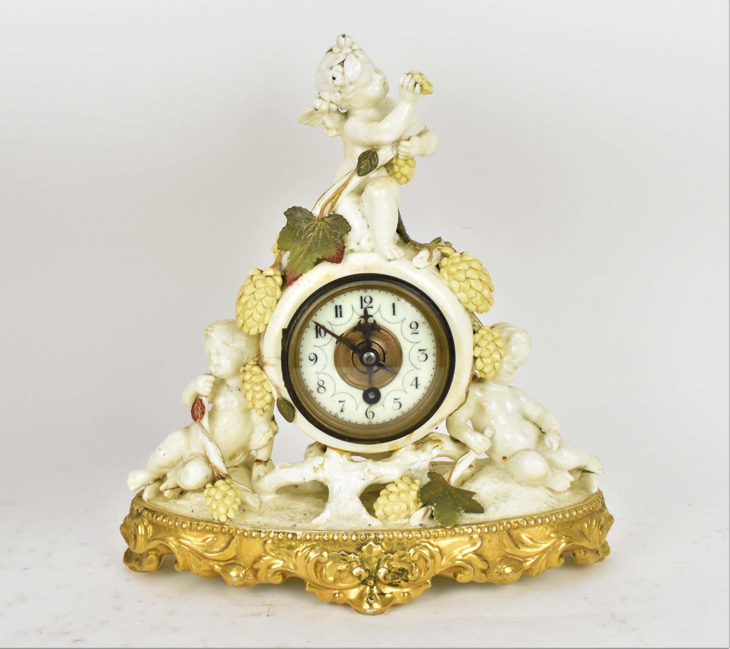 A late 19th century porcelain mantle clock, decorated with cherubs eating grapes on a gilded base,