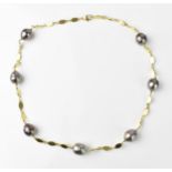 A yellow metal and baroque cultured Tahitian pearl necklace, with three flat links between each