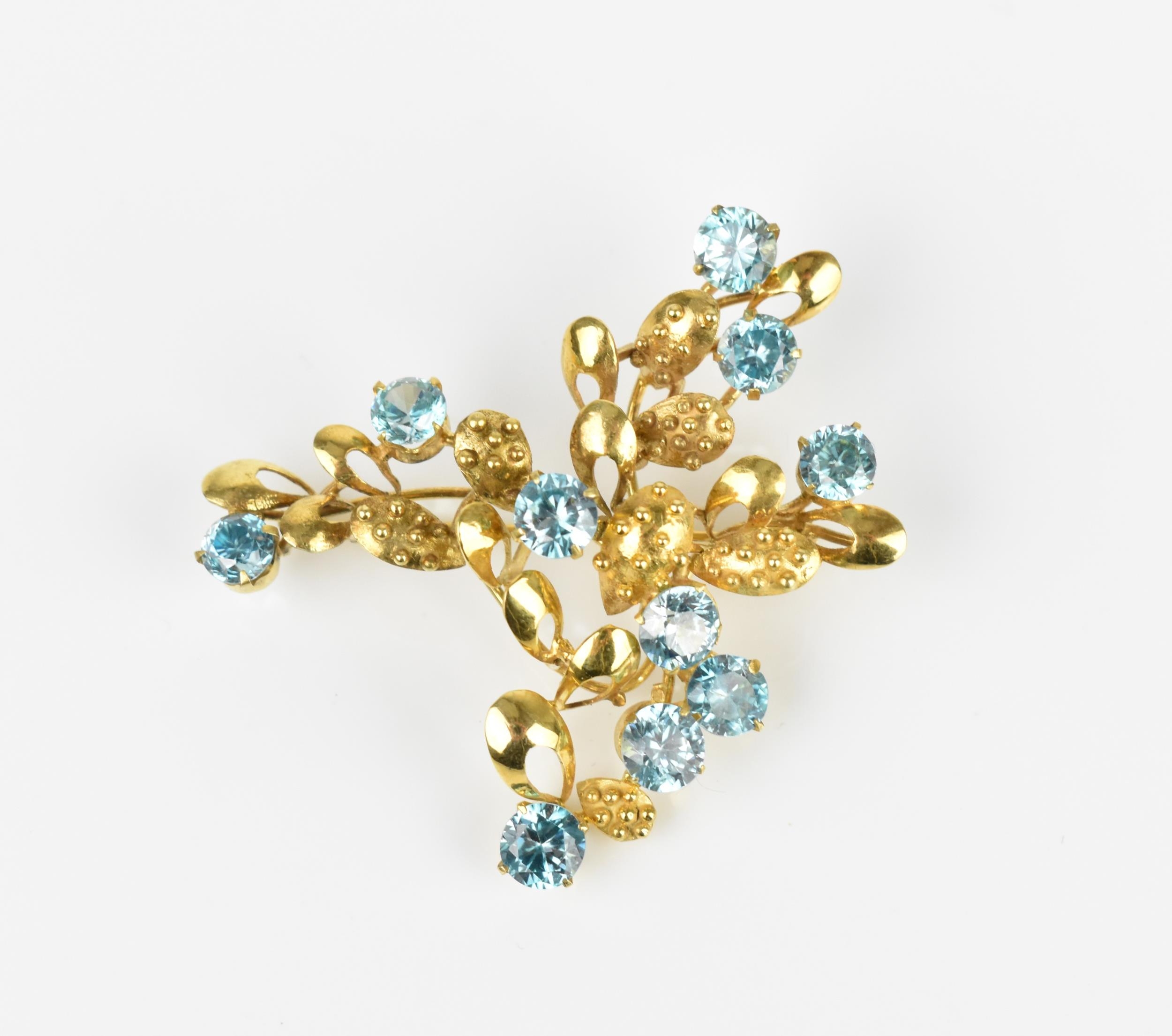 A 9ct yellow gold and blue stone floral brooch, modelled as a spray of foliage inset with round