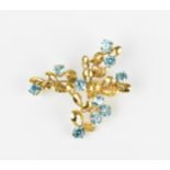 A 9ct yellow gold and blue stone floral brooch, modelled as a spray of foliage inset with round